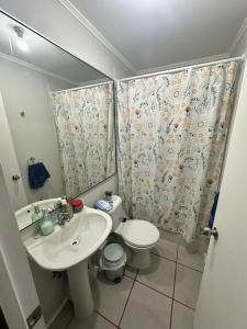 ein Badezimmer mit einem Waschbecken, einem WC und einem Duschvorhang in der Unterkunft Frente a aeropuerto in La Serena