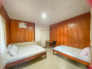 two beds in a room with wooden walls at Eashantis Place in San Vicente