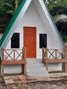 een wit huis met een rode deur en een veranda bij Dumba Bay Tioman in Tioman Island