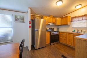 a kitchen with a stainless steel refrigerator and wooden cabinets at Stay in Ohiopyle in the center of it all, Ohiopyle, PA in Farmington