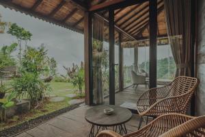 a room with a table and chairs on a patio at Kayukopi in Munduk