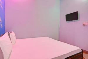 um quarto com uma cama branca e uma televisão na parede em OYO Hotel The Paradise Inn em Jhajjar