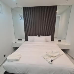 uma grande cama branca com duas toalhas brancas em White Garden Hotel em Maputo