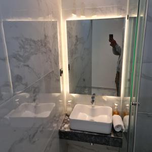 a man taking a picture of a bathroom with a sink at White Garden Hotel in Maputo