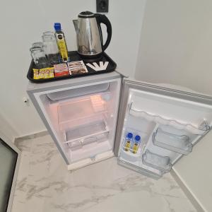 an empty refrigerator with its door open and a kettle at White Garden Hotel in Maputo