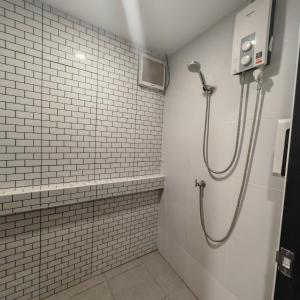 a shower in a bathroom with white tiles at A lazy person hostel in Chumphon