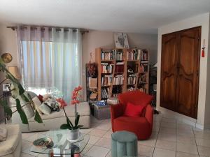 uma sala de estar com uma cadeira vermelha e uma estante de livros em Maison Tarnos, 4 pièces, 6 personnes - FR-1-239-779 em Tarnos