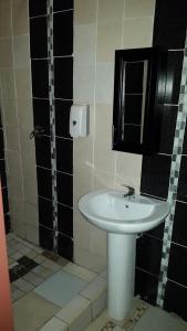 a bathroom with a white sink and black tiles at Monarchy Guest House in Johannesburg