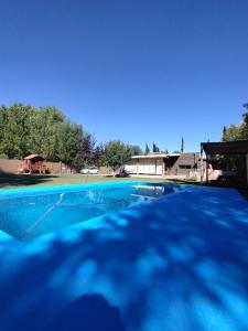 una piscina azul con una casa en el fondo en El Coiron en Colonia Las Rosas