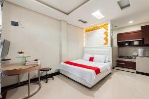 a bedroom with a bed and a desk and a kitchen at RedDoorz Syariah near Pasar Aceh Shopping Centre in Banda Aceh
