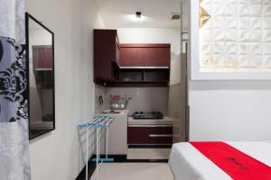a small kitchen with brown cabinets and a bed in a room at RedDoorz Syariah near Pasar Aceh Shopping Centre in Banda Aceh