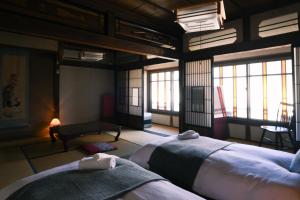 a bedroom with two beds in a room with windows at Nunoya Ryokan in Matsumoto