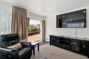 a living room with a couch and a flat screen tv at Whare 35 - Rotorua Holiday Home in Rotorua