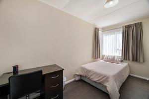a bedroom with a desk and a bed and a window at Whare 35 - Rotorua Holiday Home in Rotorua