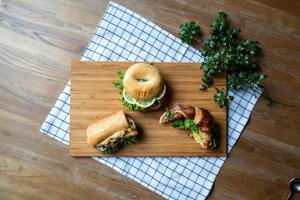 ein Holzschnitttafel mit einem Sandwich und einem Bagel in der Unterkunft Hotel Anteroom Kyoto in Kyoto