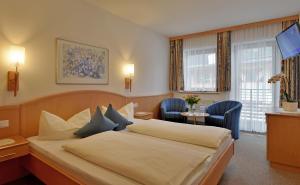 een hotelkamer met een bed, een tafel en stoelen bij Hotel Garni Jennewein in Mayrhofen