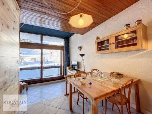 una sala da pranzo con tavolo in legno e finestra di Studio Duplex Lumineux · Front de Neige · 4 Pers · Balcon · Piscine Chauffée - FR-1-267-282 a Villarembert