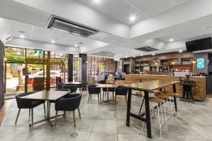 Comfort Hotel Adelaide Meridien في أديلايد: مطعم بطاولات وكراسي وبار