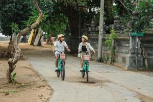 two people riding bikes down a street at Sri Phala Resort & Villa in Sanur