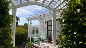 two chairs sitting under a white pergola at Rustling Oaks NZ Tropical Tiny House in Tamahere