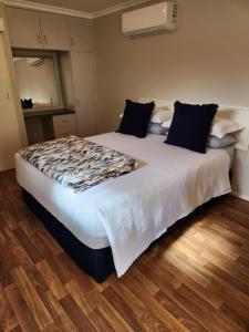 a large bed in a room with a wooden floor at Ferns Miners Rest Motel in Mount Morgan