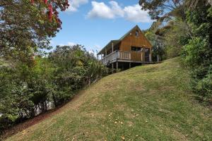 a wooden house on top of a hill at Macrocarpa Cottage - Cable Bay Holiday Home in Cable Bay