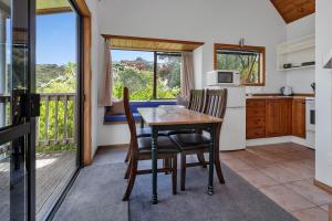 eine Küche und ein Esszimmer mit einem Tisch und Stühlen in der Unterkunft Macrocarpa Cottage - Cable Bay Holiday Home in Cable Bay