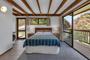 ein Schlafzimmer mit einem Bett und einem Balkon in der Unterkunft Macrocarpa Cottage - Cable Bay Holiday Home in Cable Bay