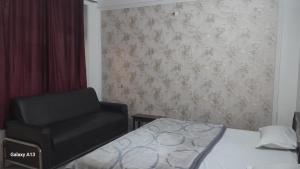1 dormitorio con 1 cama y 1 silla negra en HOTEL UDAY RAJ, en Agra
