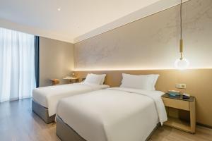 2 camas en una habitación de hotel con sábanas blancas en The Skytel Hotel Shenzhen Central Park, en Shenzhen