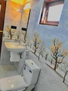 a bathroom with a toilet and a sink with trees on the wall at LSC Villa in Weligama