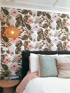 a bedroom with a floral accent wall and a bed with flowers at Rustling Oaks NZ Tropical Tiny House in Tamahere