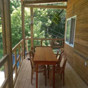 einen Holztisch und Stühle auf der Veranda einer Hütte in der Unterkunft TOnat Caribe Hostel in West End