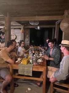 eine Gruppe von Menschen, die um einen Holztisch sitzen in der Unterkunft Dao's House Hoang Nong in Lá Cam