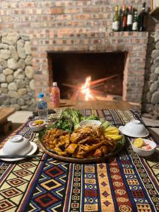 a table with a plate of food in front of a fireplace at Dao's House Hoang Nong in Lá Cam