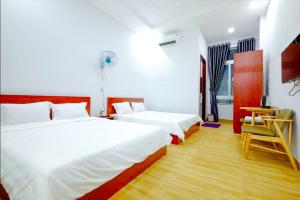 a bedroom with two beds and a table and a chair at The Luxury Pool Villa Vung Tau in Vung Tau