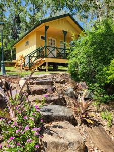 a yellow house with a porch and some flowers at Ferns Miners Rest Motel in Mount Morgan