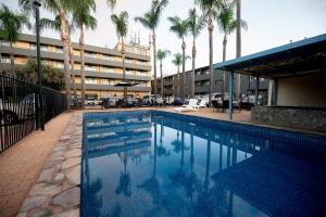 a swimming pool in front of a building with palm trees at Econo Lodge North Adelaide in Adelaide