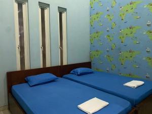 The 8 House – Surabaya City Center في سورابايا: سريرين في غرفة ذات أغطية زرقاء