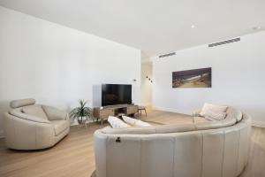 uma sala de estar com dois sofás brancos e uma televisão em Swainson at Del Monte em Henley Beach South