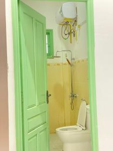 a green door leading to a bathroom with a toilet at The Green Burrow - Nhà vườn mùa hè Đà Lạt in Da Thanh