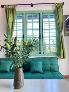 a green couch in a living room with a vase on a table at The Green Burrow - Nhà vườn mùa hè Đà Lạt in Da Thanh