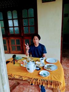 un hombre está sentado en una mesa con comida en ARANI HOMESTAY, en Polonnaruwa
