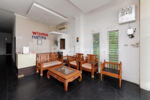a waiting room with wooden chairs and a table at RedDoorz at Wisma Nabila Banda Aceh in Banda Aceh