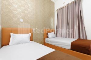 a bedroom with two beds and a window at RedDoorz at Wisma Nabila Banda Aceh in Banda Aceh