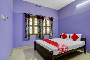 a bedroom with purple walls and a bed with red pillows at OYO Flagship Paradise villa in Cherai Beach