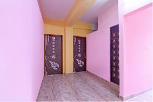 an empty room with pink and yellow walls and wooden doors at The Blue Pearl Hotel in Kolkata