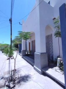 un bâtiment blanc avec des palmiers devant lui dans l'établissement El Cedro y su comodidad, à Loreto