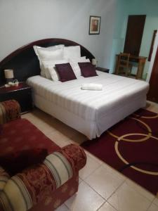 a bedroom with a large bed with white sheets and purple pillows at Ocean View Guest House in Port St. Johns