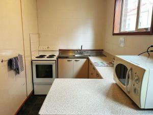 a kitchen with a stove and a sink and a microwave at Cumberland Motel in Dunedin +8 photos